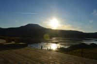 una puesta de sol sobre un cuerpo de agua con una montaña en The Tide, en Dunvegan