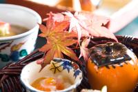 TAKITEI Riverside Onsen ーA Hidden Ryokan in Kanazawaー في كانازاوا: سلة طعام مزينة بأوراق الخريف وشمعة