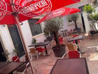 ein Restaurant mit Tischen und Stühlen mit roten Sonnenschirmen in der Unterkunft Hôtel & Restaurant ISVARA in Breteuil