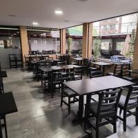 uma sala de jantar com mesas, cadeiras e janelas em Pousada e Restaurante Vila Dona Gloria no Guarujá