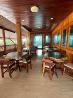 een eetkamer met tafels, banken en ramen bij Ruen Singhanat Cafe & Resort in Ban Lum Thonglang (2)