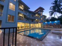 Una vista exterior de una casa con piscina. en Hotel Lotus, en Candolim