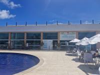 ポルト・デ・ガリーニャスにあるMuro Alto Condomínio Clubeのスイミングプール、テーブル、傘付きの建物