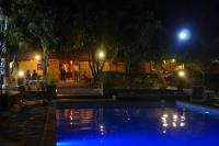 una piscina por la noche con gente sentada en una mesa en Isalo Ranch, en Ranohira