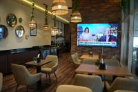 a restaurant with tables and chairs and a tv at Treppan Hotel & Suites By Fakhruddin in Dubai