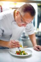 un hombre en una cocina preparando un plato de comida en Hotel Stein - Schiller's Manufaktur, en Coblenza