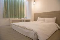 a bedroom with a large white bed and a window at Haogong Hotel in Taichung