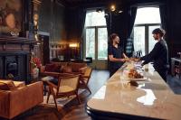 zwei Personen, die um einen Tisch in einem Zimmer stehen in der Unterkunft The Elephant Hostel in Amsterdam