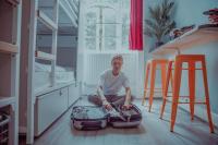 a man sitting on the floor in a room with a suitcase at Astor Hyde Park Hostel in London