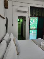 a bedroom with a white bed and a bathroom at Pousada São Francisco in Cumuruxatiba