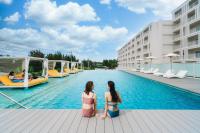 two women sitting on the edge of a pool at a hotel at BEB5 Okinawa Seragaki by Hoshino Resorts in Onna