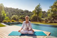 a woman sitting on a yoga mat next to a pool at Mandarin Oriental, Bodrum in Golturkbuku