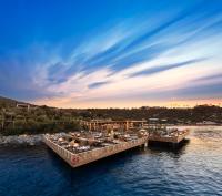two boats docked in the water with a restaurant at Mandarin Oriental, Bodrum in Golturkbuku