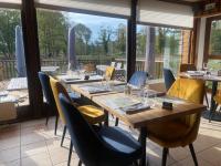 ein Esszimmer mit einem langen Holztisch und Stühlen in der Unterkunft Hôtel et Cottages Domaine Du Marquenterre in Saint-Quentin-en-Tourmont