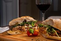 un sandwich sur une planche à découper à côté d'un verre de vin dans l'établissement CICIOSO boutique hotel, à Évora