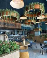 Un restaurante con mesas, sillas y plantas en macetas. en Azure Haven at Munyaka, en Midrand