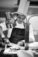 伊利索斯Blue Bay Beach Resort的一名戴着厨师帽的男子正在厨房准备食物。