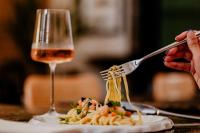 una persona che mangia pasta su un piatto con un bicchiere di vino di Palazzo Presta a Gallipoli