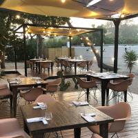 een restaurant met tafels en stoelen en een parasol bij La Palude del Conte in Punta Prosciutto