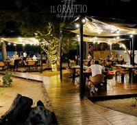 een restaurant met mensen die 's nachts aan tafel zitten bij La Palude del Conte in Punta Prosciutto