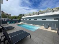 Una piscina con dos sillas y un edificio. en Karaibes Hotel, en Le Gosier