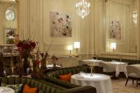 Un comedor con mesas y sillas y una lámpara de araña. en Corinthia Grand Hotel Astoria Brussels, en Bruselas