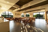 Un restaurante con mesas y sillas de madera y ventanas. en SinQ Anvaya, en Maem