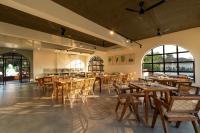 Un restaurante con mesas y sillas de madera y ventanas. en SinQ Anvaya, en Maem