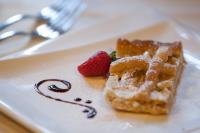 a plate with a waffle and a strawberry on it at Albergo Boule de Neige in Rhêmes-Notre-Dame