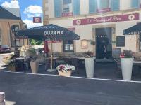 un restaurant avec un parasol, des tables et des chaises dans l'établissement Le Pourquoi pas, à La Bourboule