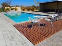 un grupo de sillas sentadas en una terraza de madera junto a una piscina en Mogale Royal Gardens, en Polokwane