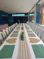a long table in a room with white chairs at Pousada do Mel- Iranduba in Iranduba