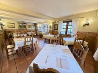 a restaurant with white tables and chairs and windows at Posada El Corcal de Liébana in Tama