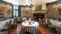 a dining room with tables and chairs and a fireplace at Château de Codignat in Lezoux