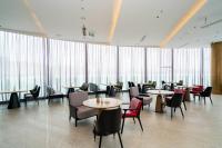 Un restaurante con mesas y sillas y grandes ventanales. en Suzhou Qingfeng Mingyue Hotel, en Yinshanhunongchang