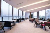 Un restaurante con mesas y sillas y grandes ventanales. en Suzhou Qingfeng Mingyue Hotel, en Yinshanhunongchang