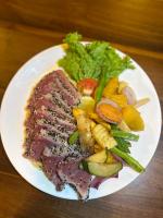 un plato de carne y hortalizas en una mesa en Lucky Monkey Inn and Restaurant, en Weligama