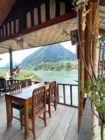 een tafel en stoelen op een terras met uitzicht op een rivier bij Rainbow Guesthouse in Ban Ngoy-Nua