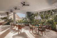 een restaurant met tafels en stoelen en palmbomen bij Almare, a Luxury Collection Resort, Isla Mujeres Cancun, Adult All-Inclusive in Isla Mujeres