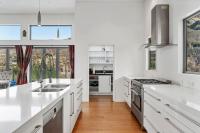 eine Küche mit weißen Arbeitsplatten und weißen Schränken in der Unterkunft Huge &amp; Stylish on Shotover 4 Bedrooms in Queenstown