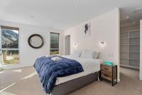 ein Schlafzimmer mit einem großen Bett und einem Spiegel in der Unterkunft Huge &amp; Stylish on Shotover 4 Bedrooms in Queenstown