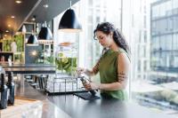 a woman is standing at a counter with a vase at citizenM Southwark Bankside in London
