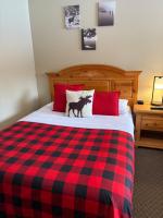 a bed with a red and black checkered blanket at Parkway Motel in Wawa