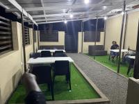 a room with tables and chairs and a person sitting at tables at Idyllic Inn in Lilongwe