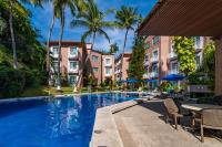 Una piscina en un hotel con sillas y palmeras. en Hotel Castillo Huatulco & Beach Club, en Santa Cruz Huatulco