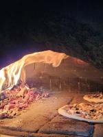 a brick oven with two pizzas cooking in it at Hôtel La Casera in Clarac