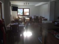 Un comedor con mesas y sillas y una ventana. en Gentiana-Sureanu, en Tău Bistra