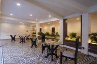 Un restaurante con mesas, sillas y plantas. en Hotel Lotus, en Candolim