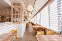 um restaurante com mesas e cadeiras de madeira e janelas em Hotel Global View Hachinohe em Hachinohe