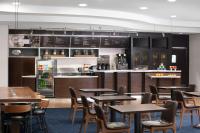 a restaurant with tables and chairs and a kitchen at Courtyard by Marriott Knoxville Airport Alcoa in Alcoa